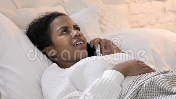 年轻的非洲女人躺在床上打电话视频的预览图