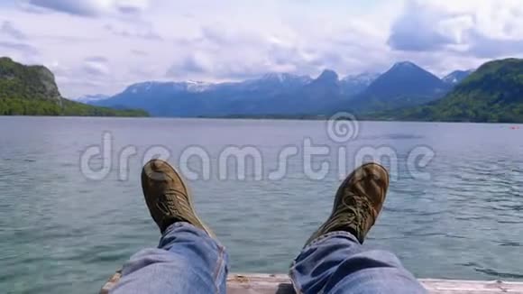 山湖和白雪覆盖的山脉背景上的人类腿视频的预览图