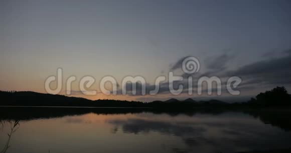 美丽的日出天空在一个风景优美的湖泊上方一只白天鹅在日出时游过湖视频的预览图