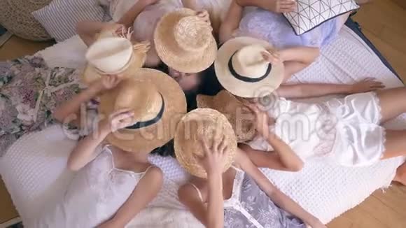 穿着睡衣的快乐女朋友躺在床上脸上戴着草帽然后脱下她们在镜头前微笑视频的预览图
