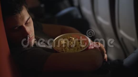 睡觉的人在电影院拥抱爆米花盒在电影院的椅子上睡觉的家伙视频的预览图