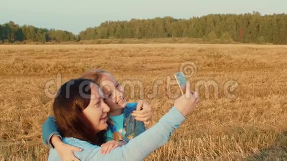 快乐的母女在麦田拍自拍照给智能手机视频的预览图