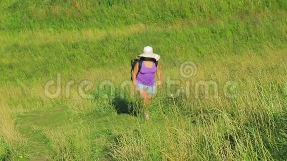 一个戴着草帽背着背包的女人沿着小路爬上了山从顶部射击视频的预览图