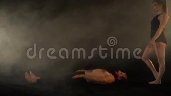 在烟雾中的男人和女人都在支撑下做杂技瑜伽慢动作视频的预览图