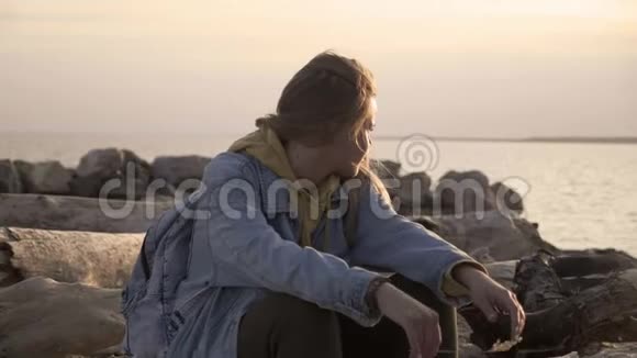 不高兴的女孩坐在海滩上看日落视频的预览图