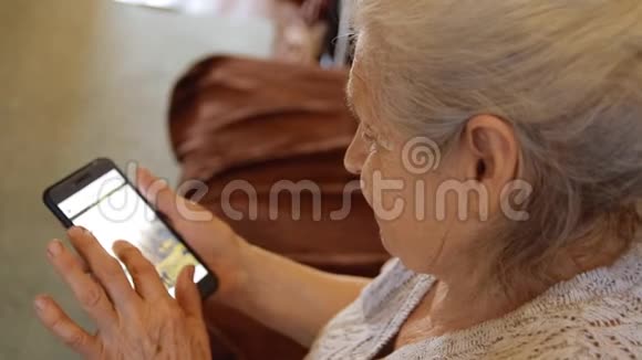 一位老妇人用智能手机观看社交网络的特写镜头视频的预览图