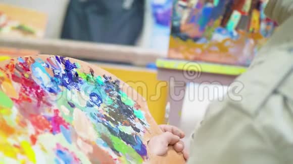 艺术家的一个特写他的手握着画笔和调色板画画在工作室里帆布视频的预览图