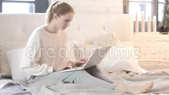 坐在床上工作的年轻女子视频的预览图
