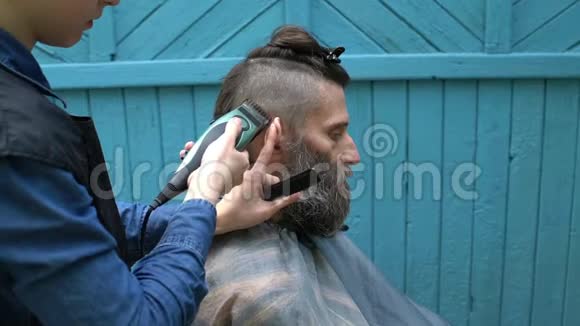 女理发师用电动剃须刀和梳子给留胡子的帅哥理发视频的预览图
