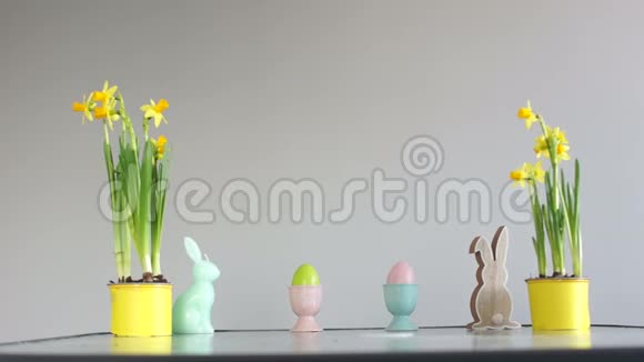 孩子们手绑架装饰的鸡蛋复活节装饰在桌子上盆栽水仙花兔雕像视频的预览图