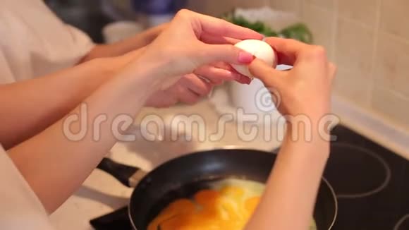 两个苗条的女孩在家准备一份煎蛋卷她们把鸡蛋打碎成煎锅视频的预览图