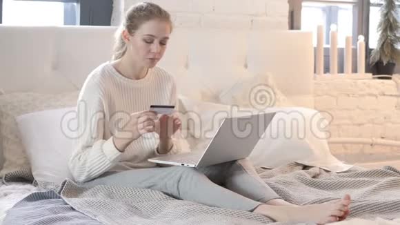 坐在床上的女人成功的网上购物视频的预览图