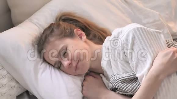 有头痛躺在床上的年轻女子的俯视图视频的预览图