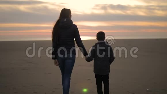 妈妈和她的儿子在日落时沿着海滨散步视频的预览图