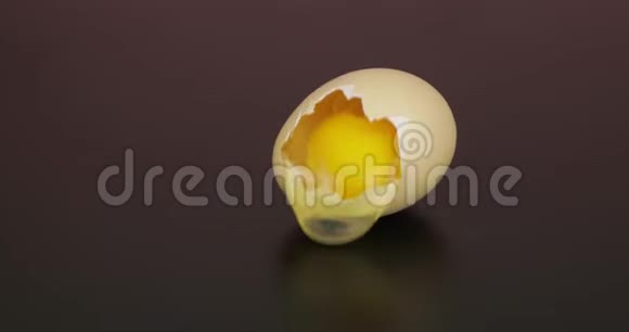 鸡蛋黄从破碎的蛋壳中倒入黑色表面视频的预览图