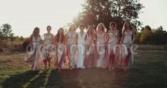 惊人的美丽新娘与她的团队女孩与波霍风格的裙子走在惊人的日落慢动作视频的预览图