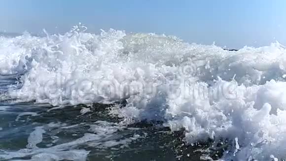 大风缓慢地向岸边挥手特写海浪的浪花在阳光下闪闪发光视频的预览图