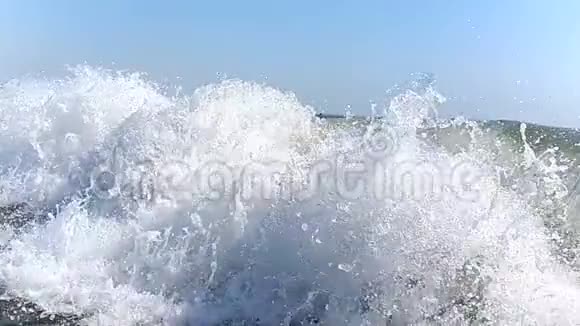 大风缓慢地向岸边挥手特写海浪的浪花在阳光下闪闪发光视频的预览图