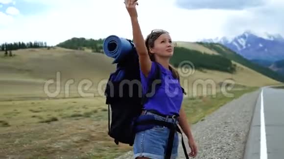 年轻的旅游妇女带着背包和太阳镜试图在山路上捕捉电话信号有很多视频的预览图
