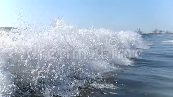 大风缓慢地向岸边挥手特写海浪的浪花在阳光下闪闪发光视频的预览图