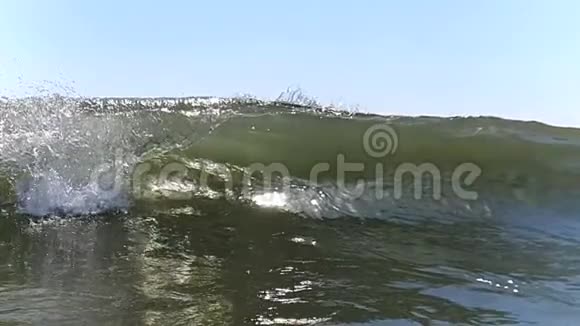 大风缓慢地向岸边挥手特写海浪的浪花在阳光下闪闪发光视频的预览图