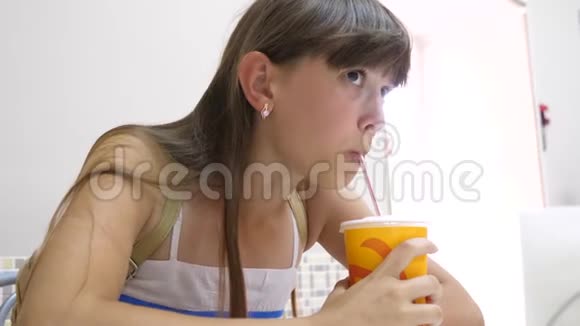 美丽的女孩坐在咖啡馆的桌子旁喝着鸡尾酒微笑着视频的预览图