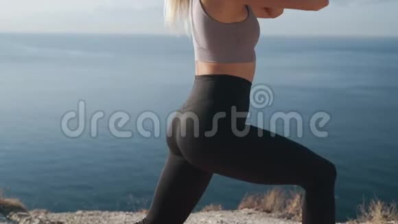 女人蹲在户外的垫子里训练她的身体看海景慢动作视频的预览图