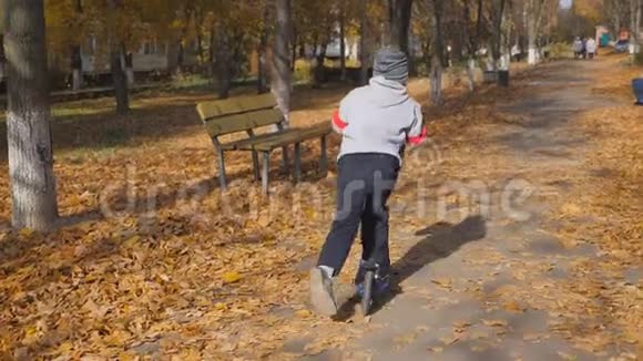 孩子骑滑板车小男孩用脚推开骑在木板上孩子拿着方向盘视频的预览图