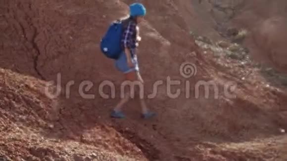 年轻的女游客带着背包和帽子从红石山下来视频的预览图