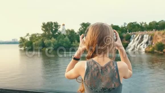 年轻女子戴上耳机听音乐欣赏大自然视频的预览图