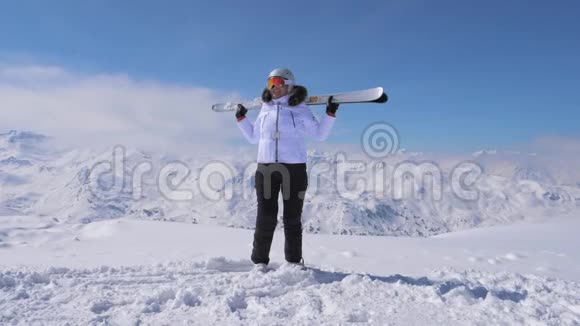 女滑雪者站在斜坡山上举起滑雪板挥动4K视频的预览图