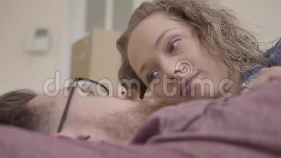 特写男女躺在一起说话的画像戴眼镜的长胡子男人卷发的漂亮女人视频的预览图