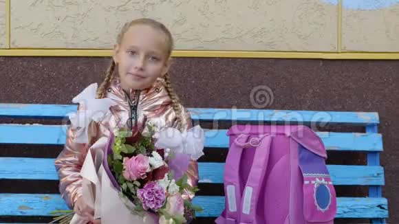 快乐的学校女孩带着花束坐在长凳上回到学校的概念视频的预览图
