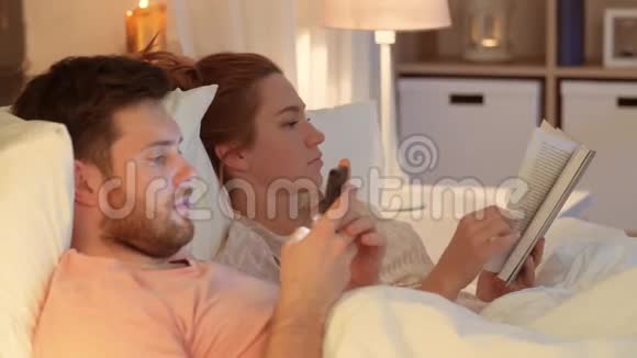 带智能手机的情侣晚上在床上看书视频的预览图