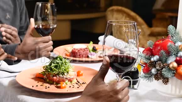 新年节日餐桌用红酒举起酒杯的男性手的特写镜头餐桌上的圣诞装饰视频的预览图