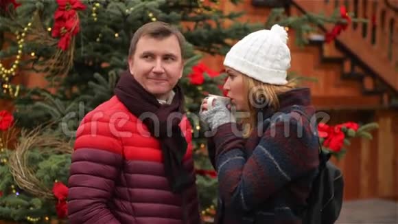 帅哥和美女在传统的圣诞市场上喝咖啡妻子和丈夫互相看视频的预览图
