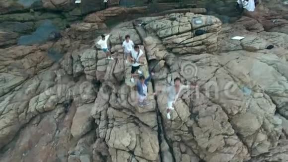 亚洲年轻人在海边的岩石上行走视频的预览图