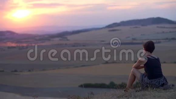 女孩坐在山上望着远处的山视频的预览图