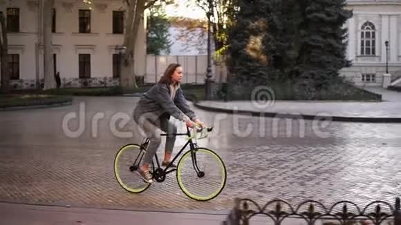 女人骑自行车在城市铺路女自行车骑手早上骑自行车空城街道与美丽视频的预览图