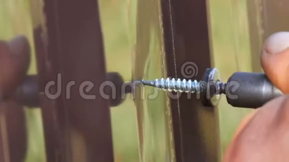 手动螺丝刀和螺丝切入铁钣金近景男人手在修理栅栏视频的预览图