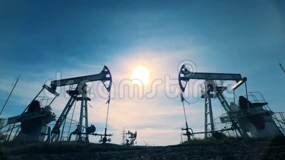日落背景下的石油开采化石燃料能源油泵抽油机工作视频的预览图