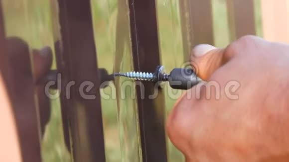 手动螺丝刀和螺丝切入铁钣金近景男人手在修理栅栏视频的预览图