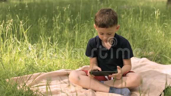 公园里草地上有平板电脑的男孩视频的预览图