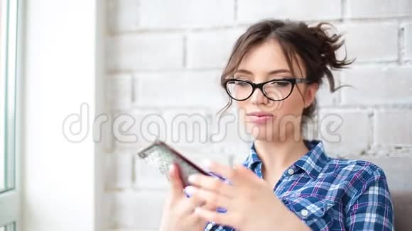 一张漂亮的白种人穿格子衬衫的女人在智能手机上说话的肖像脸上挂着微笑视频的预览图