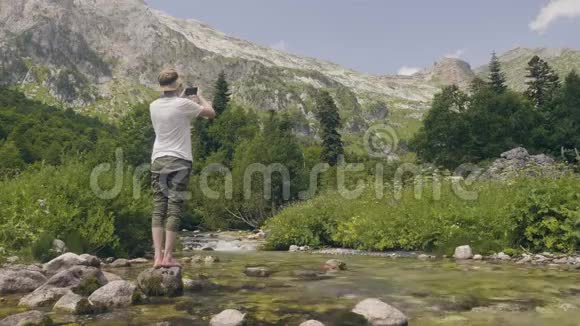 旅游人员在旅游时用手机拍摄山河景观视频的预览图
