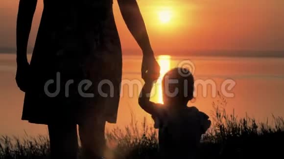 日落时分母亲和婴儿正穿过田野去河边家庭幸福视频的预览图