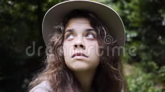 戴帽子的女人看着绿林间的小径视频的预览图