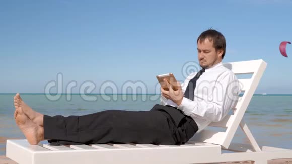 年轻的商人正在海滩上工作男专业人士坐在舒适的休息室里视频的预览图