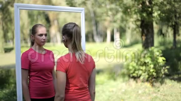 两个穿着运动服的双胞胎女孩在公园里照镜子视频的预览图