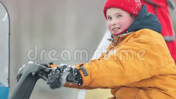 冬天一个小男孩坐在雪地车上拧着煤气手柄视频的预览图